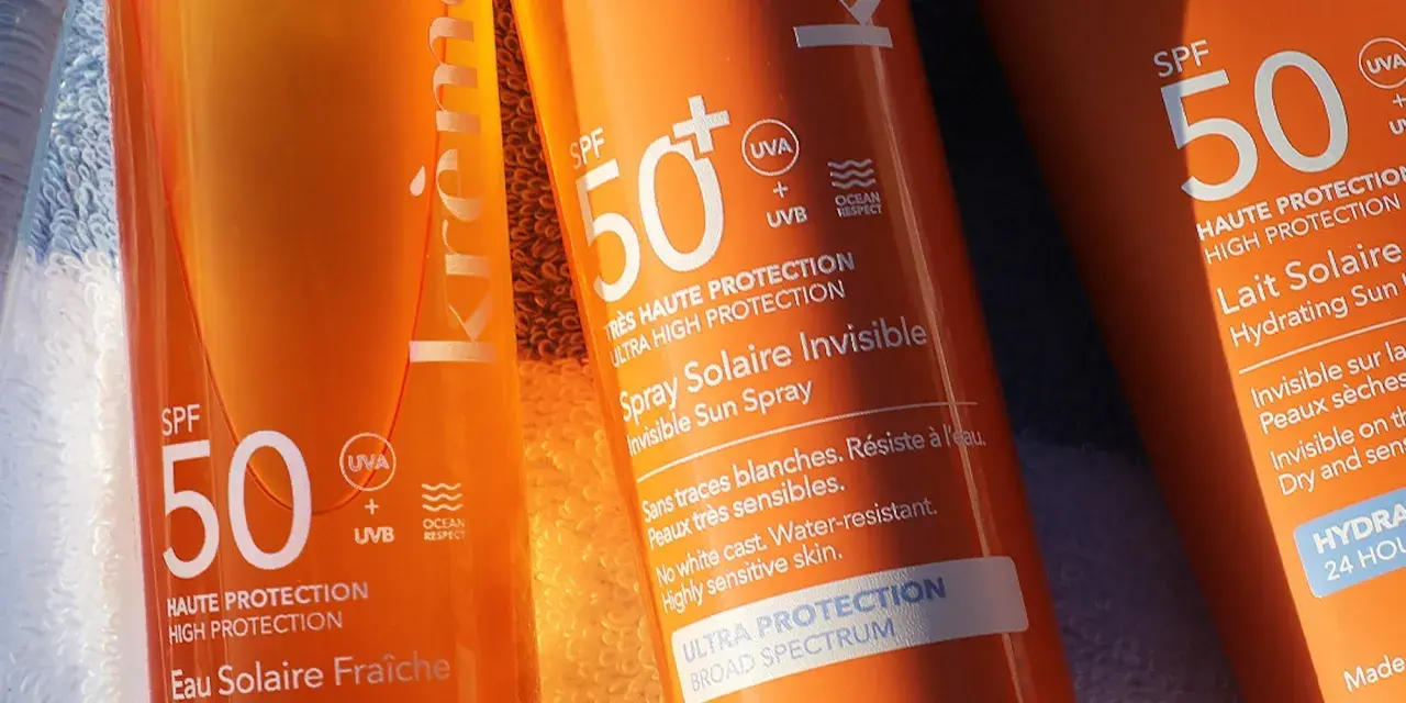 Trois tubes de crème solaire, tous avec SPF 50, prêts pour la protection solaire. L'un est un spray invisible, l'autre un lait hydratant.
