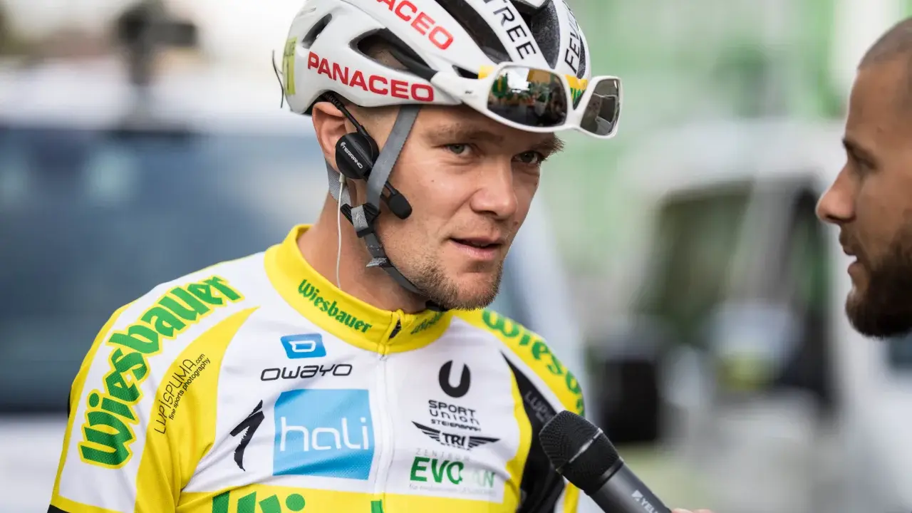 Radsportler mit Helm und Mikrofon, bereit für ein Interview nach einem harten Rennen, vielleicht dem Race Across America.
