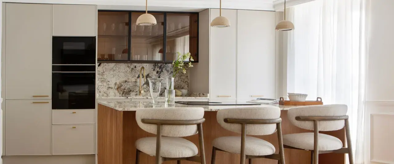Cocina moderna con isla central, taburetes y electrodomésticos integrados. Un diseño atemporal que combina funcionalidad y elegancia.