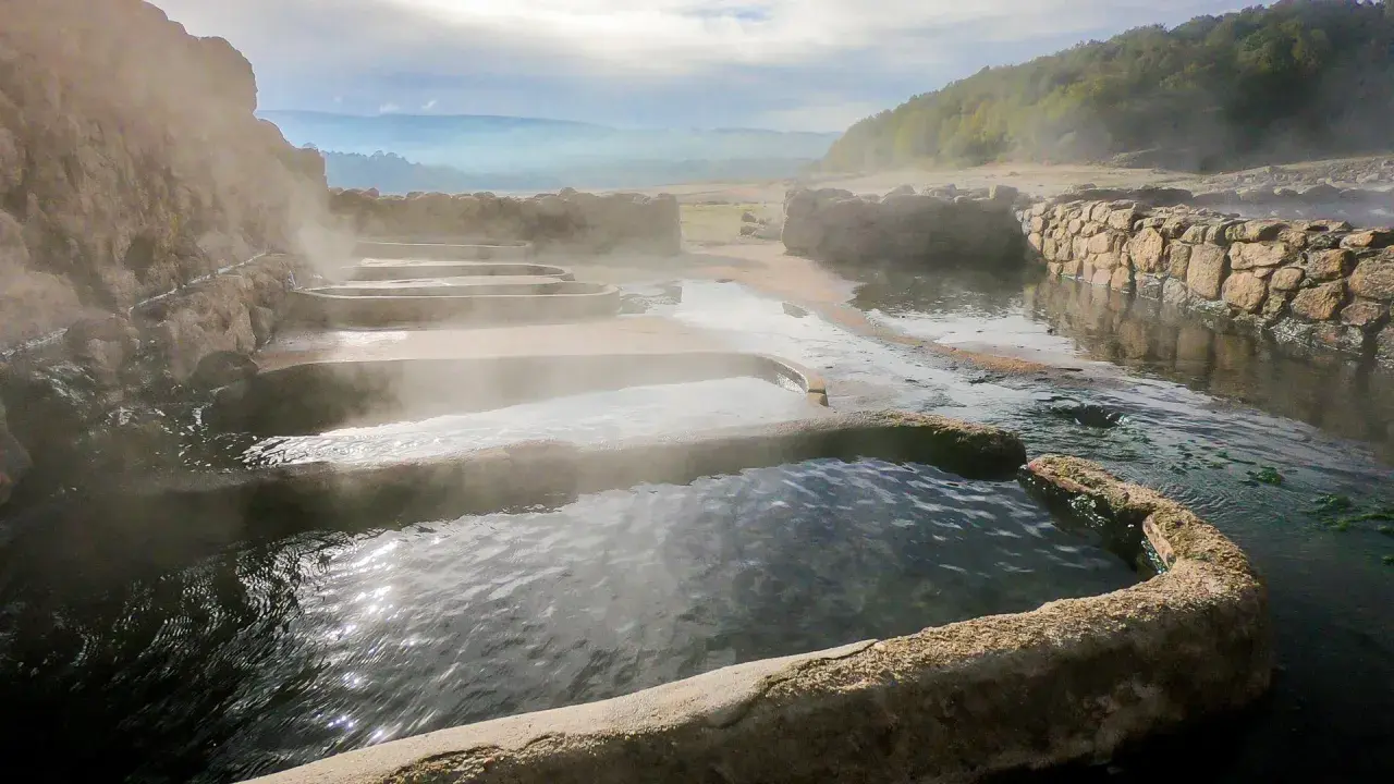 Tierras de vapor y agua en las termas naturales Galicia. Un paisaje sereno con piscinas escalonadas y muros de piedra.