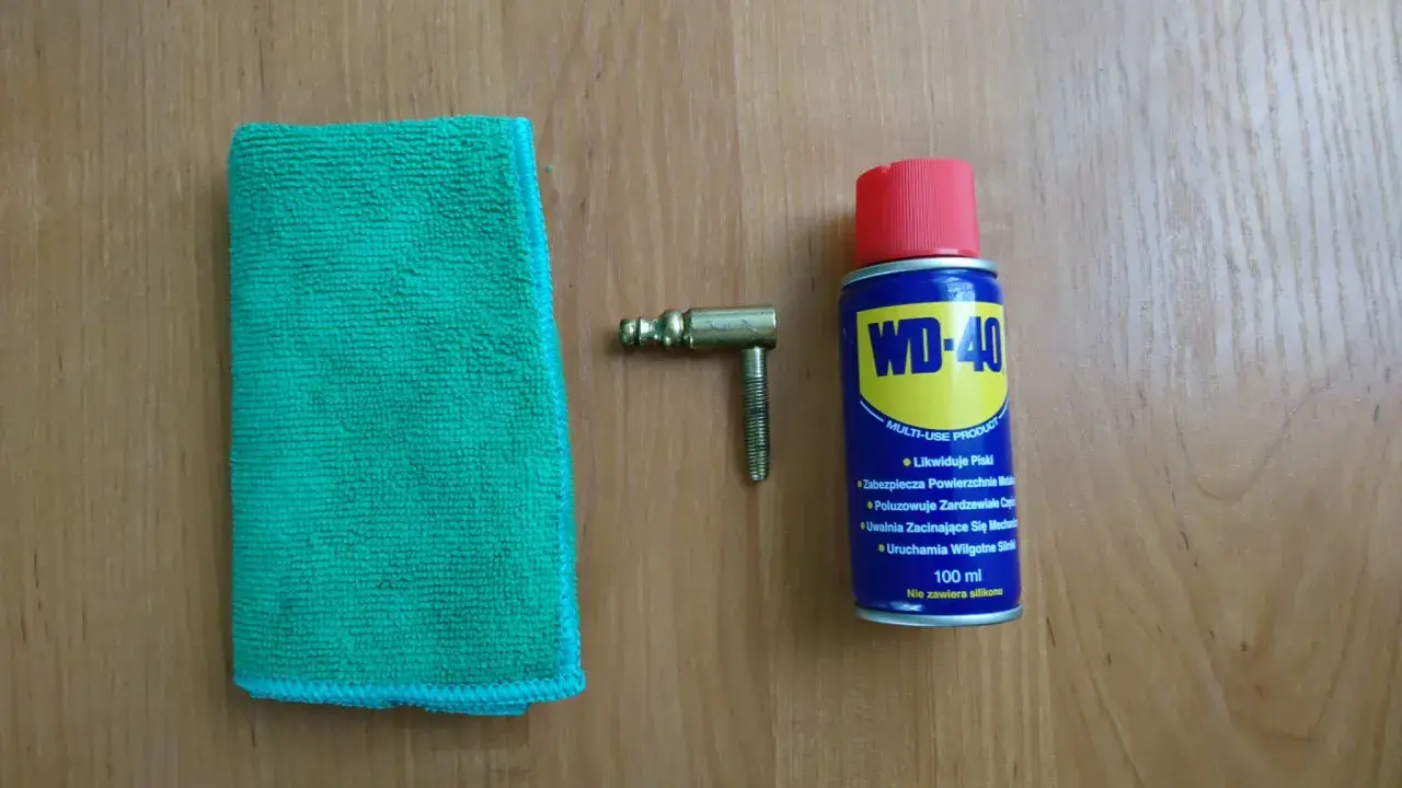 Ściereczka, mosiężny element i puszka WD-40 – wszystko gotowe do czyszczenia mosiądzu.