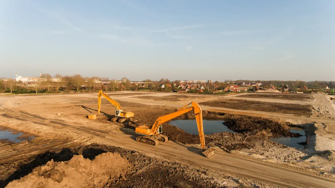 Excavadoras trabajan en un sitio de remediación de suelos, moviendo tierra y agua para restaurar el terreno.