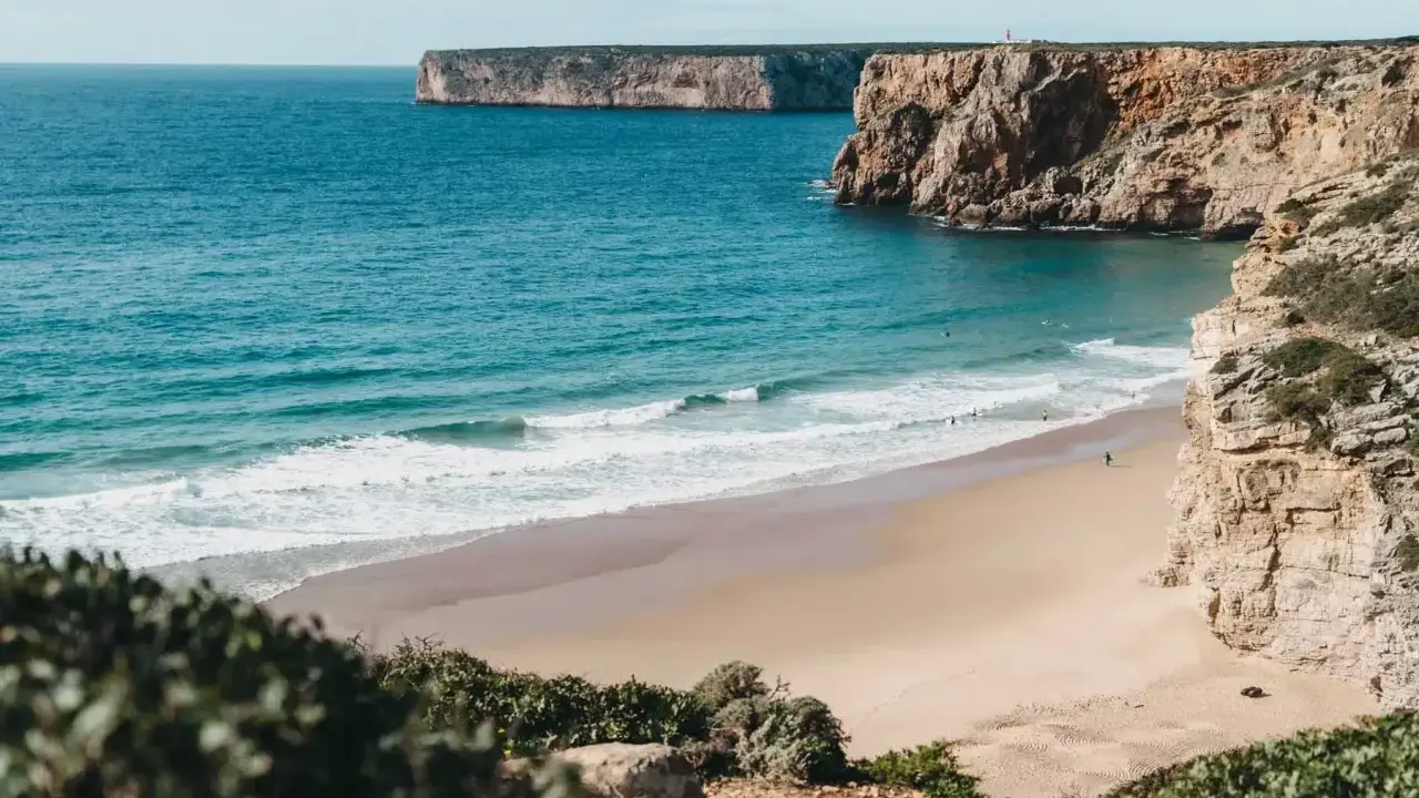 Ein einsamer Surfer genießt die Wellen am Sagres Strand, umgeben von steilen Klippen und dem weiten Atlantik.