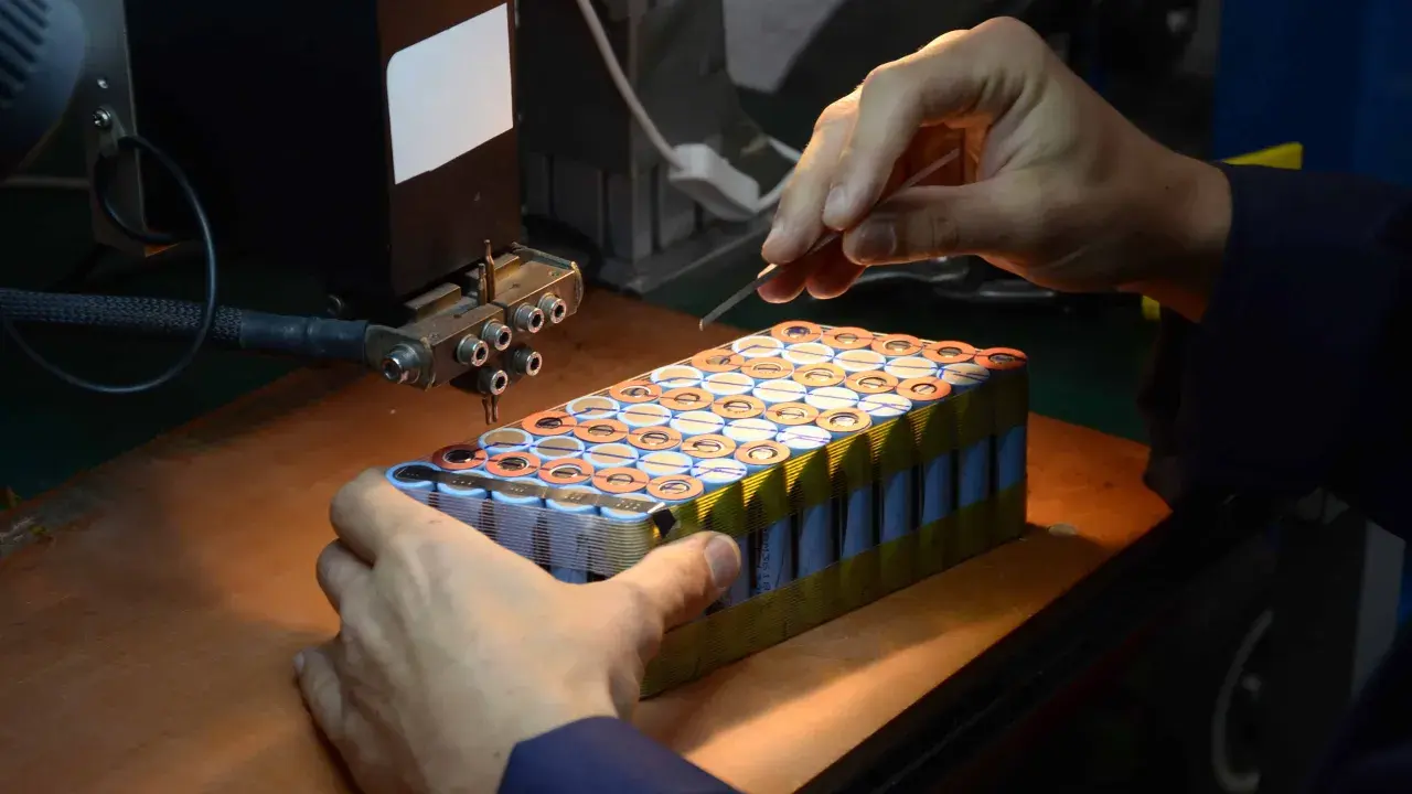 Un technicien assemble des cellules pour comment reparer une batterie de velo electrique. Il utilise un outil de soudure par points.