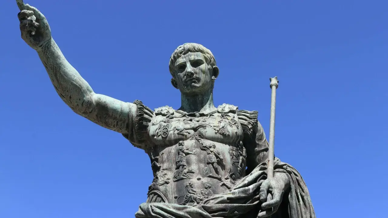 Bronzestatue eines römischen Kaisers, der mit erhobener Hand und Zepter auf den Betrachter blickt. Sie symbolisiert, wie wurde Rom regiert.