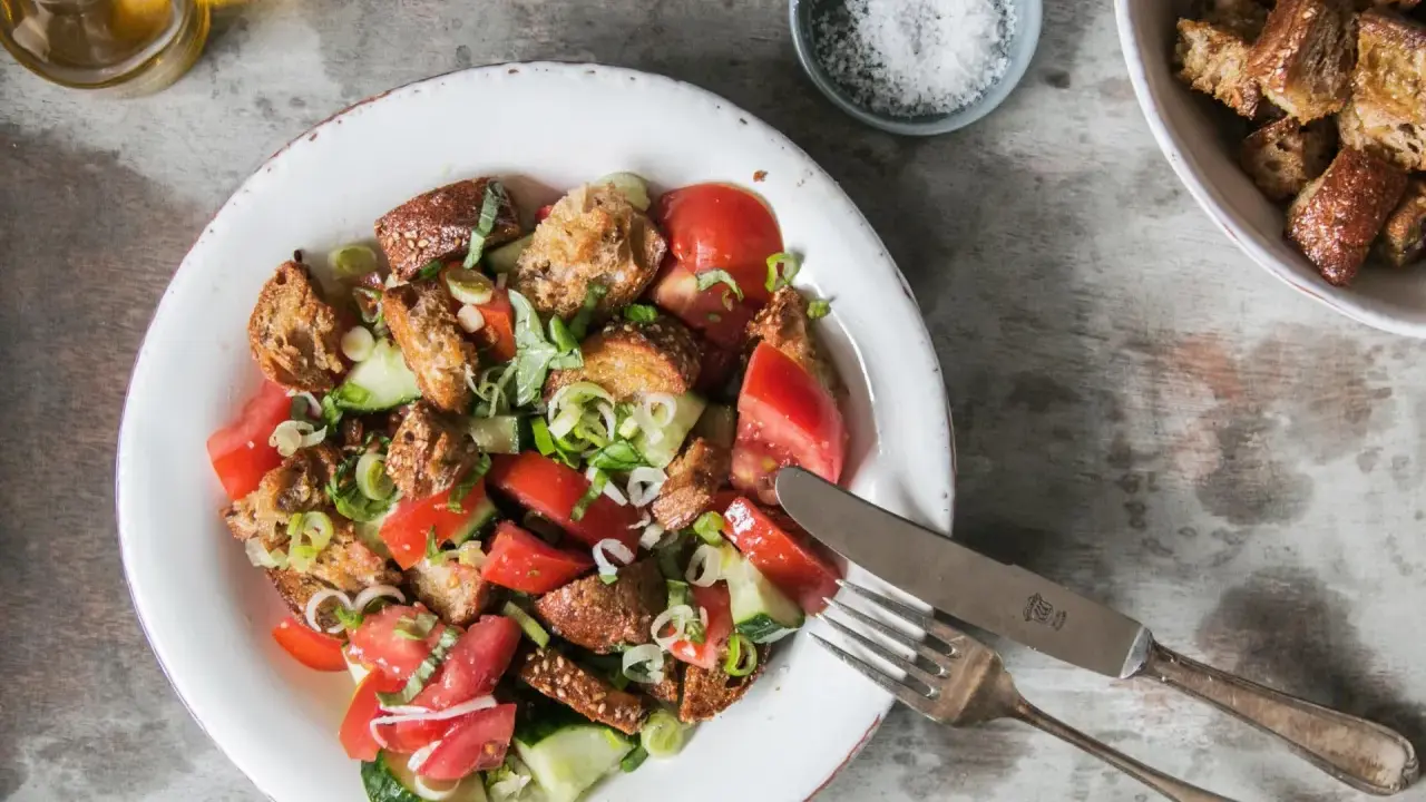 Ein erfrischender toskanischer Brotsalat mit Tomaten, Gurken und knusprigen Brotwürfeln, garniert mit frischen Kräutern.