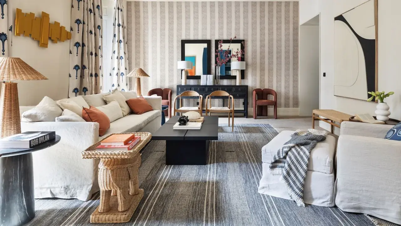 Elegante sala de estar con sofás blancos, mesa de centro negra y alfombras a rayas que complementan la decoración de la casa.
