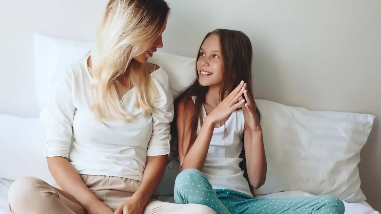 Mama i córka rozmawiają na łóżku. To świetny sposób na to, jak spędzać czas z 10 latkiem, budując więź i zrozumienie.