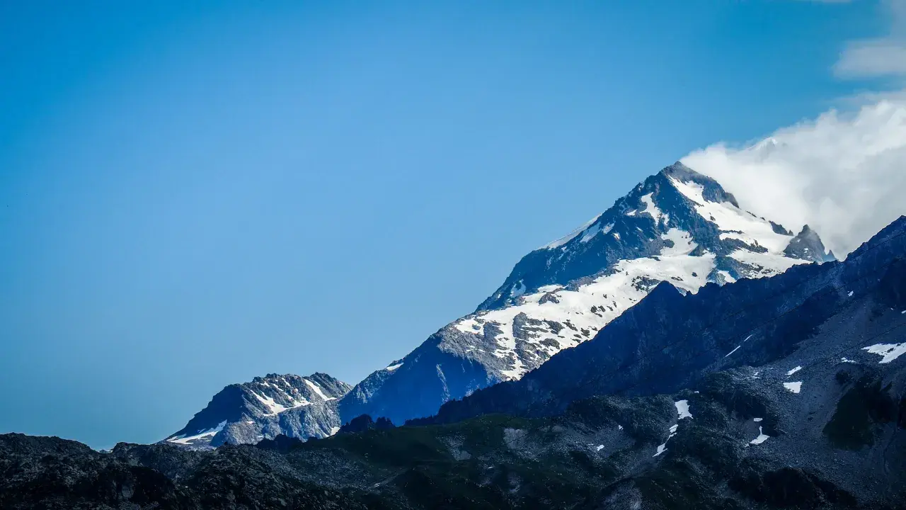 Majestatyczne szczyty Alp, pokryte śniegiem, z błękitnym niebem. Widok na trasę Tour du Mont Blanc.