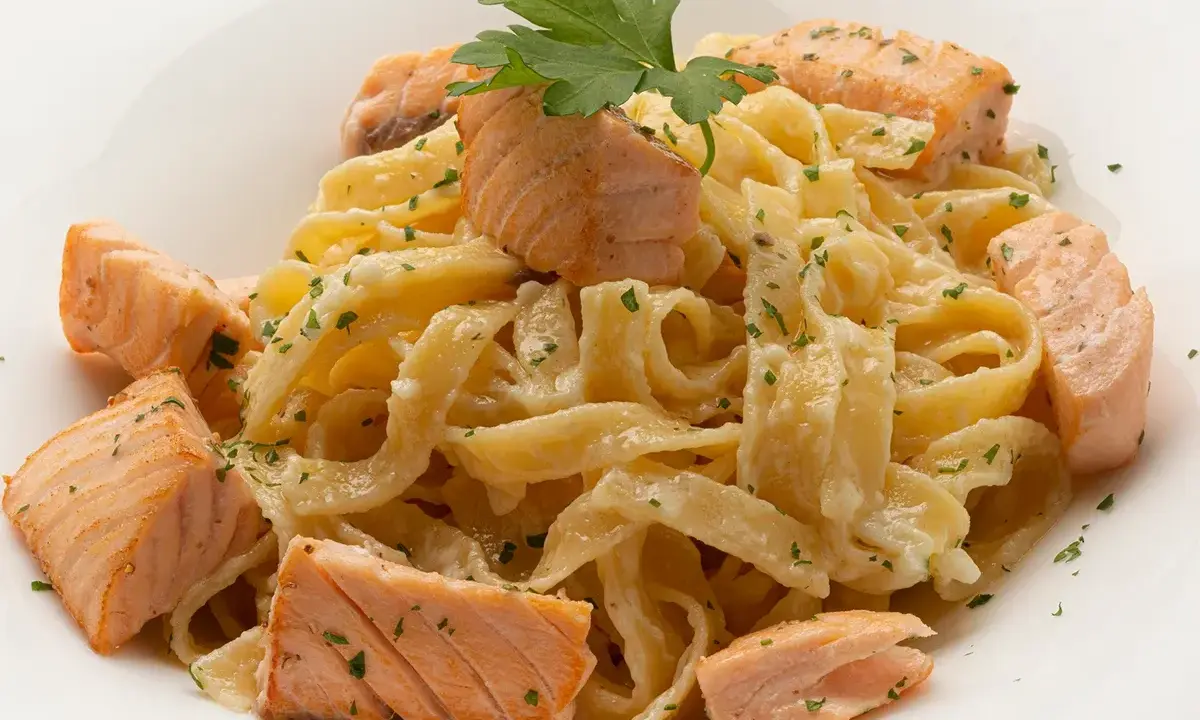Deliciosa pasta con trozos de salmón rosado, cubierta con una cremosa salsa y espolvoreada con perejil fresco.