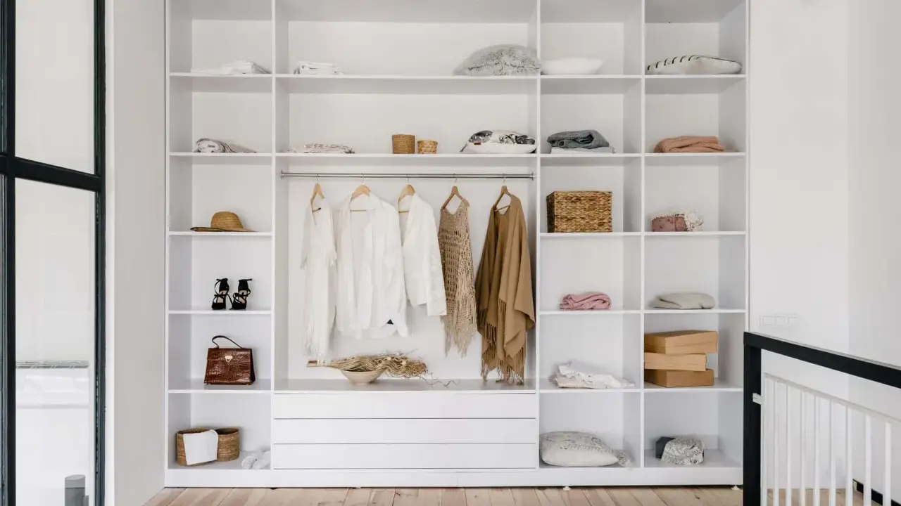 Idéal pour aménager un placard : étagères blanches remplies de vêtements, accessoires et boîtes.