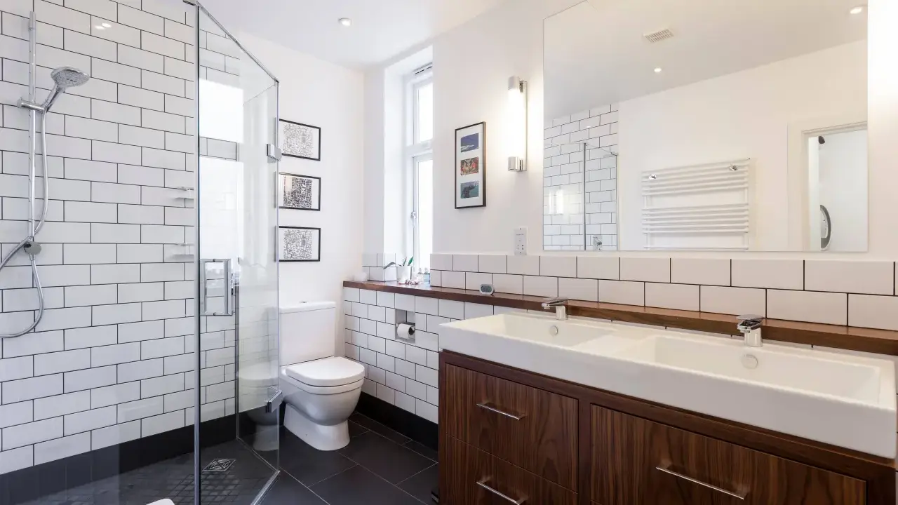 Baños modernos y reformados con plato de ducha, lavabo doble y mueble de madera.