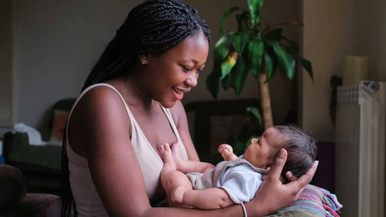 Eine junge Frau hält ihr Baby liebevoll im Arm. Die Frage "wie lange kann man stillen" beschäftigt viele Mütter.