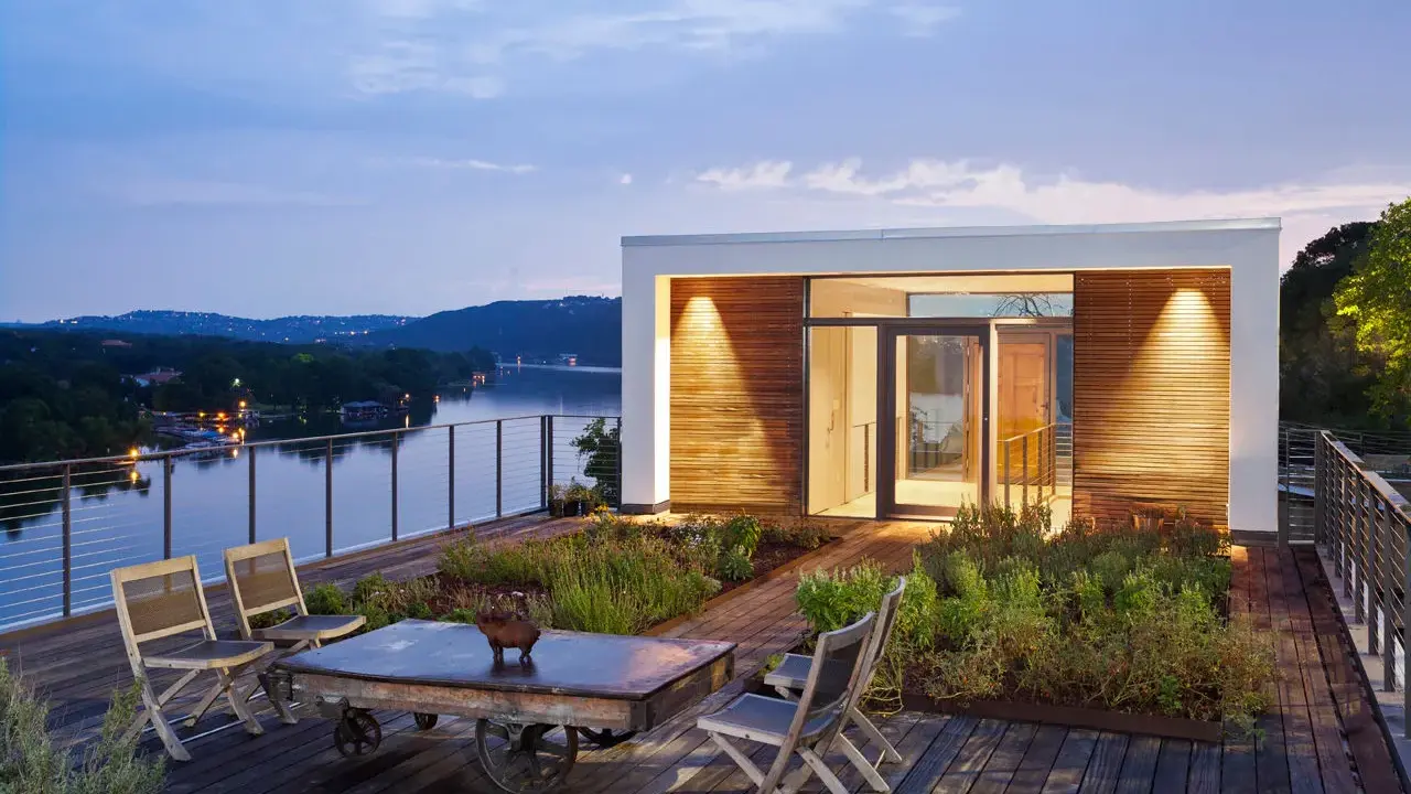 Moderner dachgarten auf einem Flachdach mit Blick auf einen See. Holzdeck, Sitzgelegenheiten und üppige Bepflanzung laden zum Entspannen ein.
