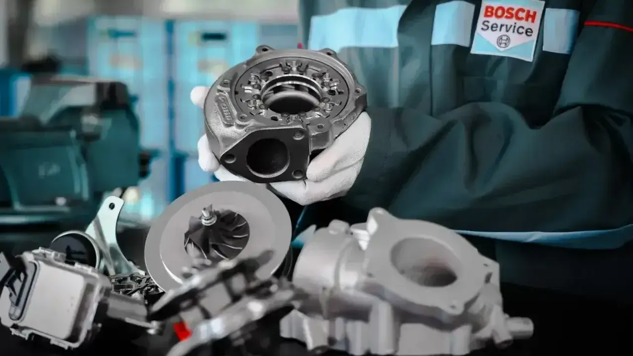 Mechanik w rękawiczkach prezentuje części turbosprężarki. Dowiedz się, ile kosztuje regeneracja turbiny w Bosch Service.