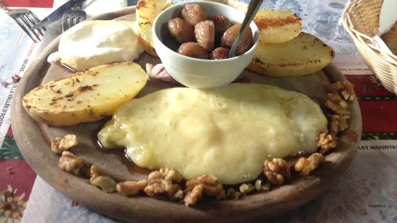 Piatto con formaggio fuso, patate arrosto, noci e cipolline. Un assaggio dei piatti tipici Valle d'Aosta.