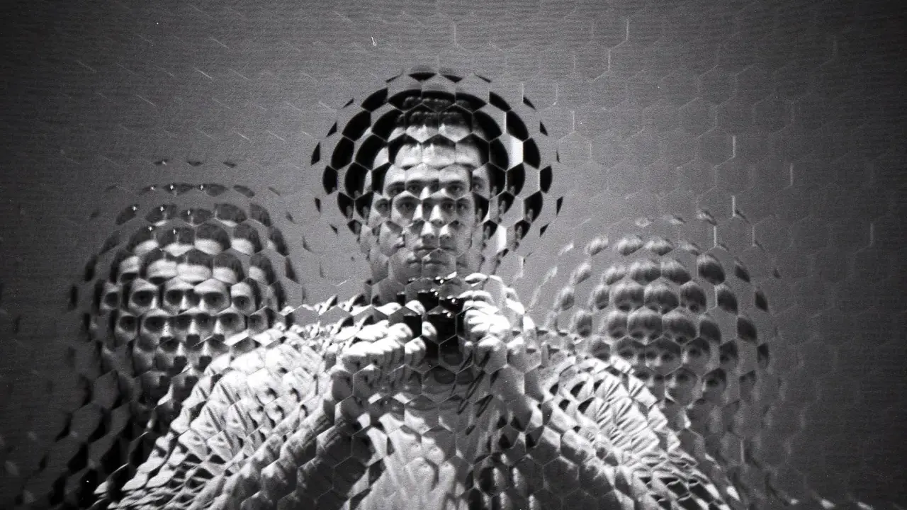 Autoritratto fotografico con volto multiplo e distorto da un effetto a nido d'ape.