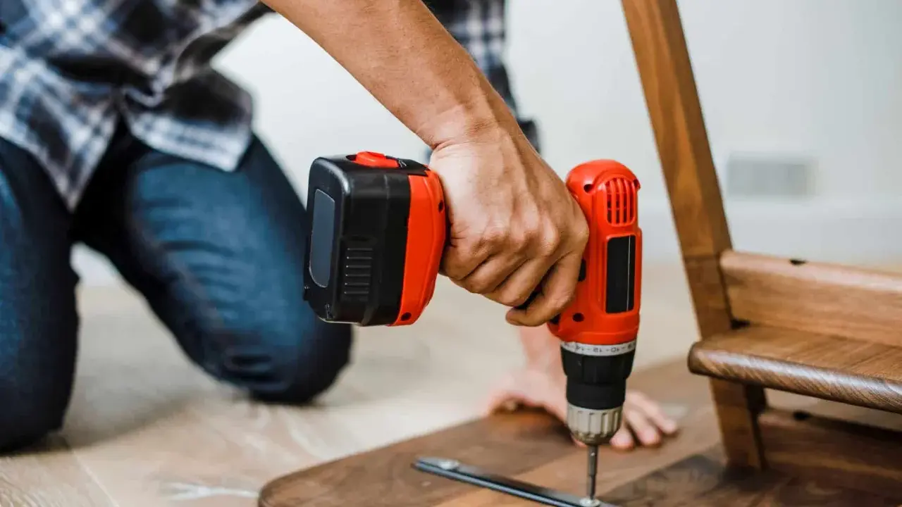 Un homme assemble un meuble en bois avec une perceuse. Un projet de bricolage maison réussi.