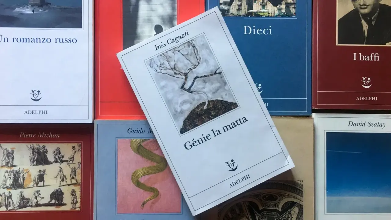 Libri Adelphi in primo piano, tra cui "Génie la matta" di Inès Cagnati, con un albero spoglio su sfondo grigio.