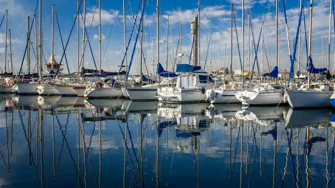 Une flotte de voiliers blancs, reflets parfaits sur l'eau calme. Un chantier naval, le constructeur bateau, a créé ces merveilles.