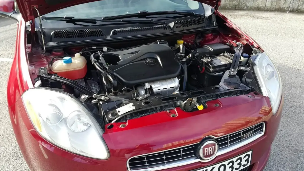 Czerwony Fiat Bravo 1.4 T-Jet z otwartą maską, widoczny silnik i reflektor.