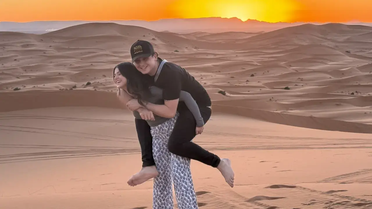 Jóvenes disfrutando de un atardecer en las dunas de Marruecos con niños.