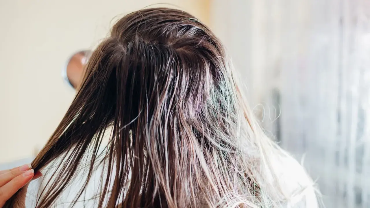 Nasse Haare, die nur mit Wasser gewaschen wurden, werden von einer Hand durchkämmt.