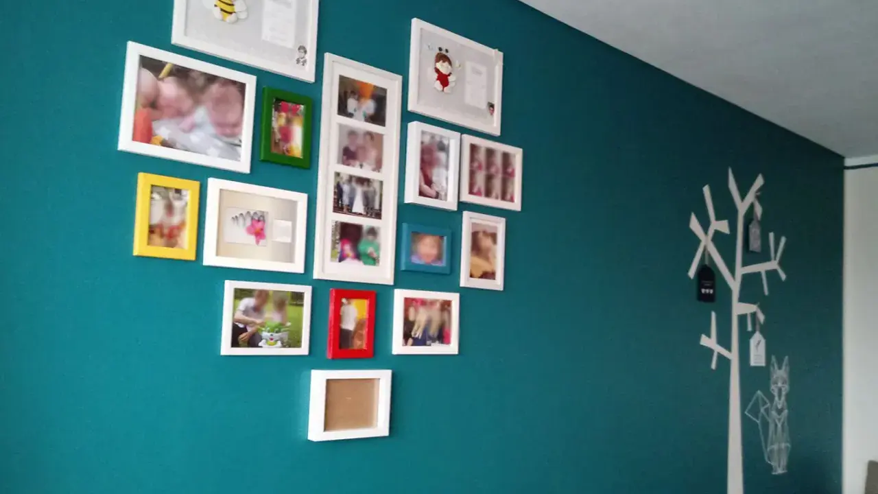 Galeria zdjęć na turkusowej ścianie, z motywem drzewa i lisa po prawej stronie.