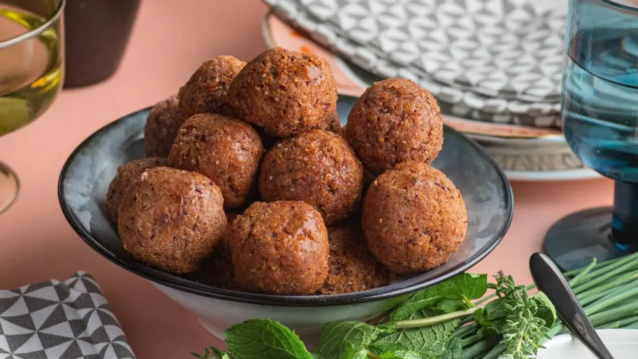 Un piatto colmo di polpette di fagioli dorate, guarnito con erbe fresche.