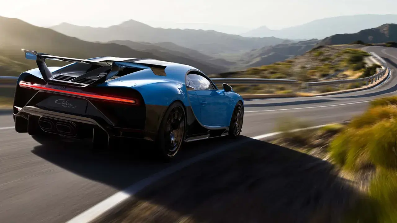 Blauer Bugatti Chiron Pur Sport rast auf einer kurvigen Bergstraße.