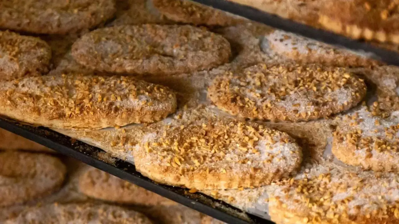 Varias cocas de llardons recién horneadas, cubiertas de azúcar y trocitos de frutos secos, listas para disfrutar.