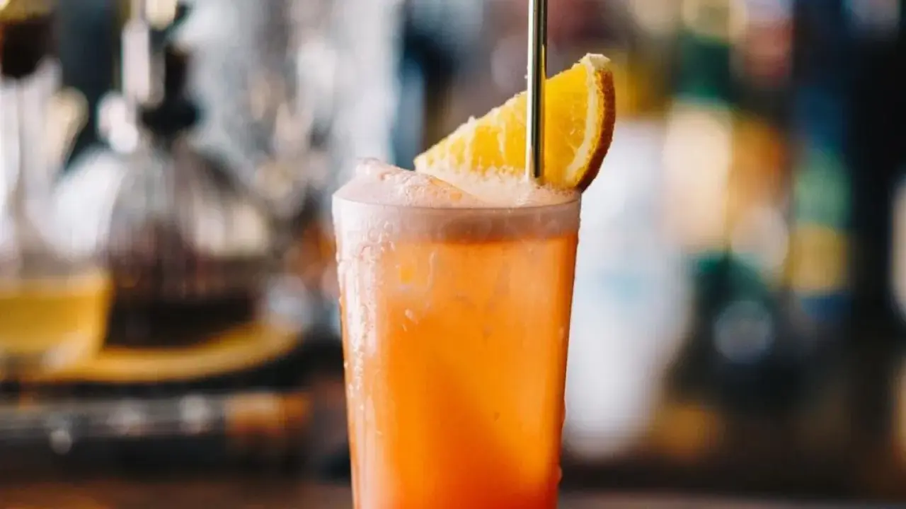 Orzeźwiający drink Garibaldi z plasterkiem pomarańczy i złotą słomką, idealny na letnie popołudnie.