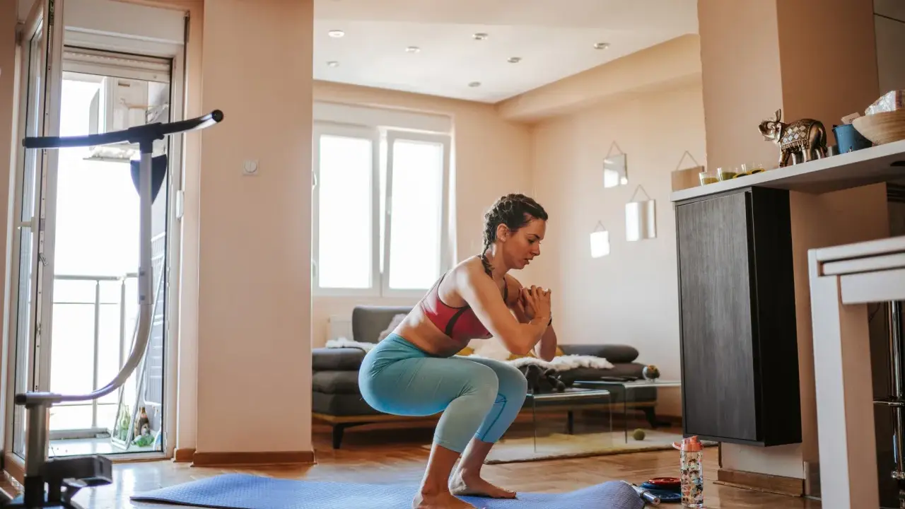 Frau macht Kniebeugen auf einer Matte, ein Beispiel für effektives **Eigengewicht Training** zu Hause.