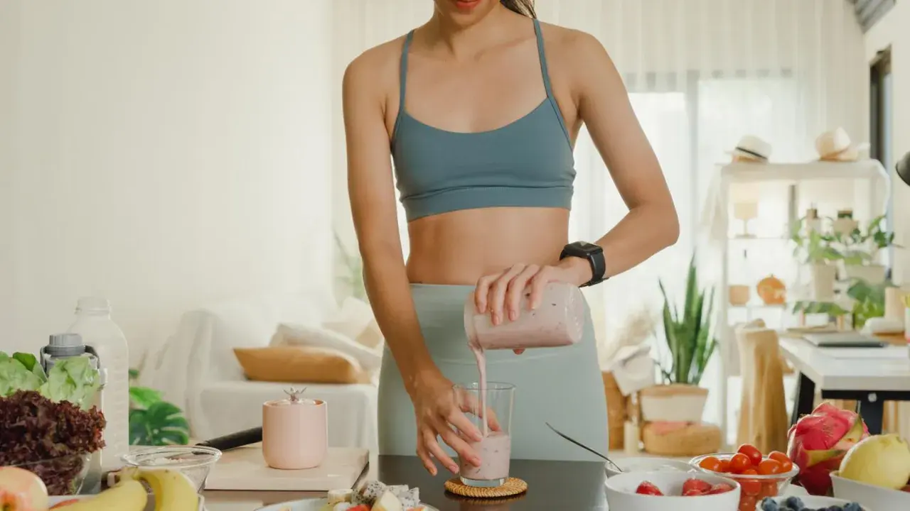 Frau bereitet einen gesunden Smoothie zu. Sie fragt sich, ob Proteinpulver beim Abnehmen hilft.