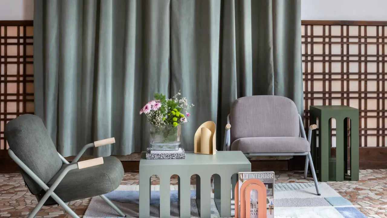 Un salotto con sedie grigie, tavolini verde salvia e un tocco di rosa pesca. Idee per colori da abbinare con il grigio chiaro.
