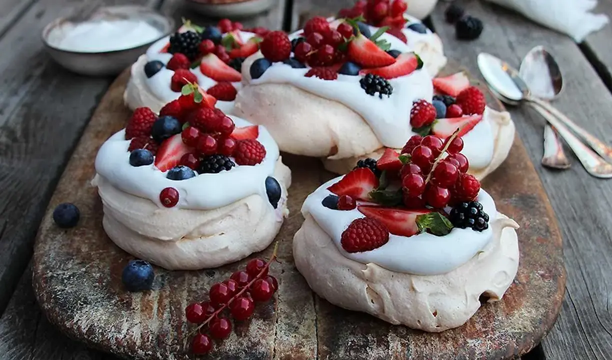 Små pavlovakakor med vispgrädde och färska bär som jordgubbar, hallon, blåbär och vinbär. En härlig sommardessert!