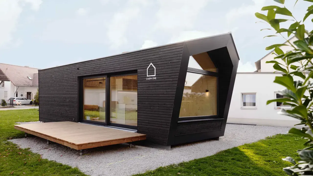 Modernes, dunkles Cabin House mit Holzterrasse und großem Fenster. Ein stilvolles Zuhause für minimalistisches Wohnen.
