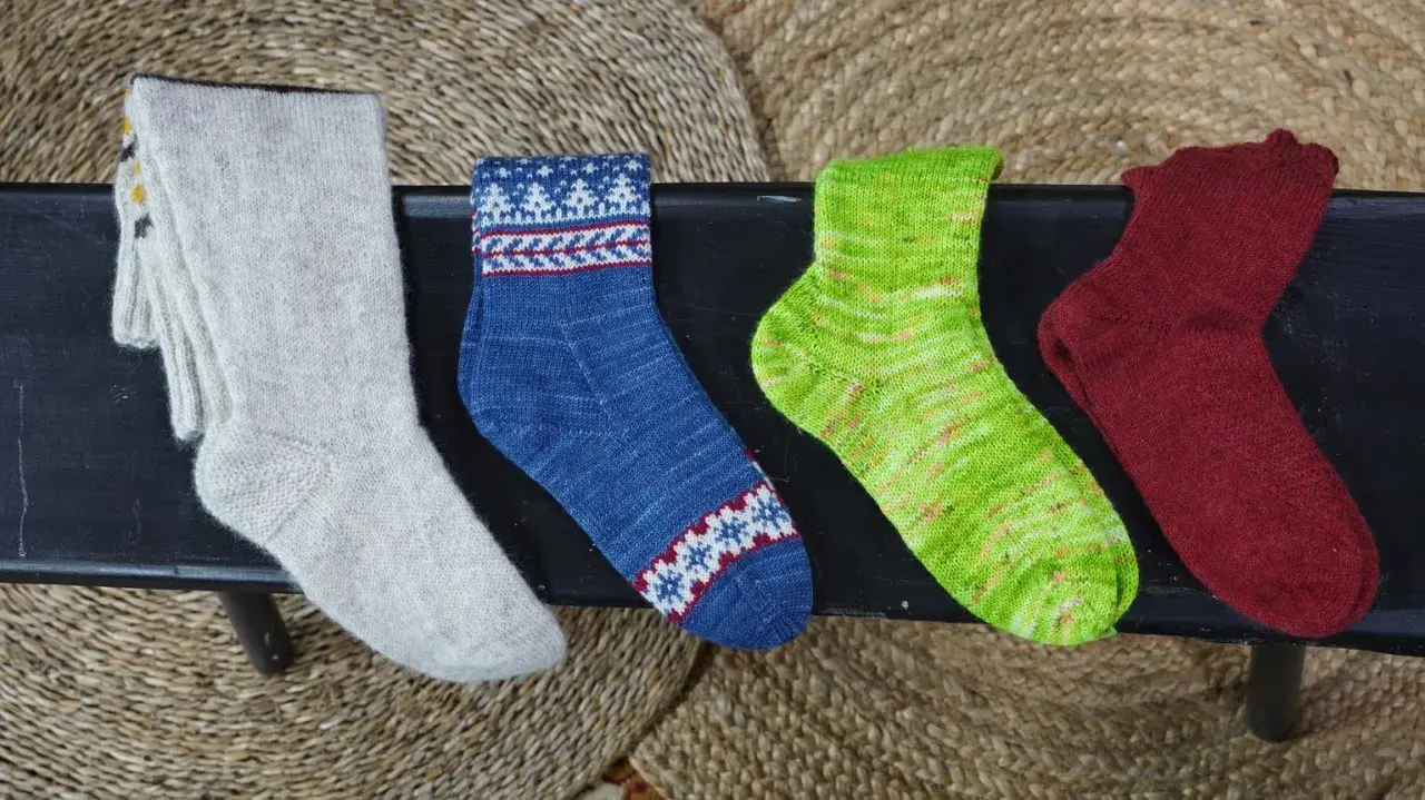Fyra par handstickade sockor i olika färger och mönster. Perfekt för att sticka enkla sockor till barn.