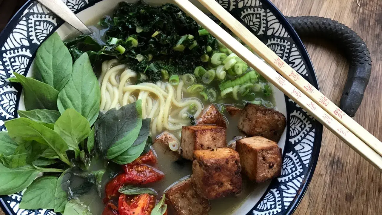 En skål med vegetarisk ramen med nudlar, tofu, grönsaker och basilika.