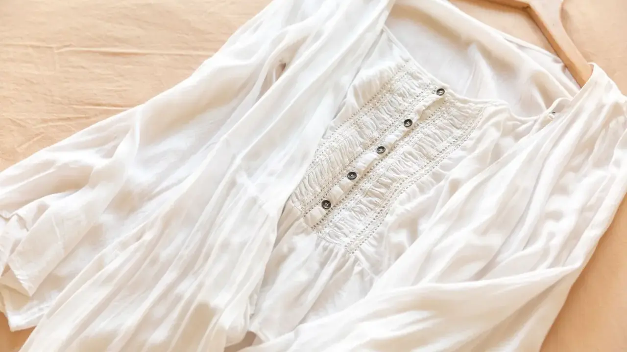 Vit blus i mjukt material rayon, med smockdetaljer och knappar framtill. Lätt och luftig, perfekt för sommaren.