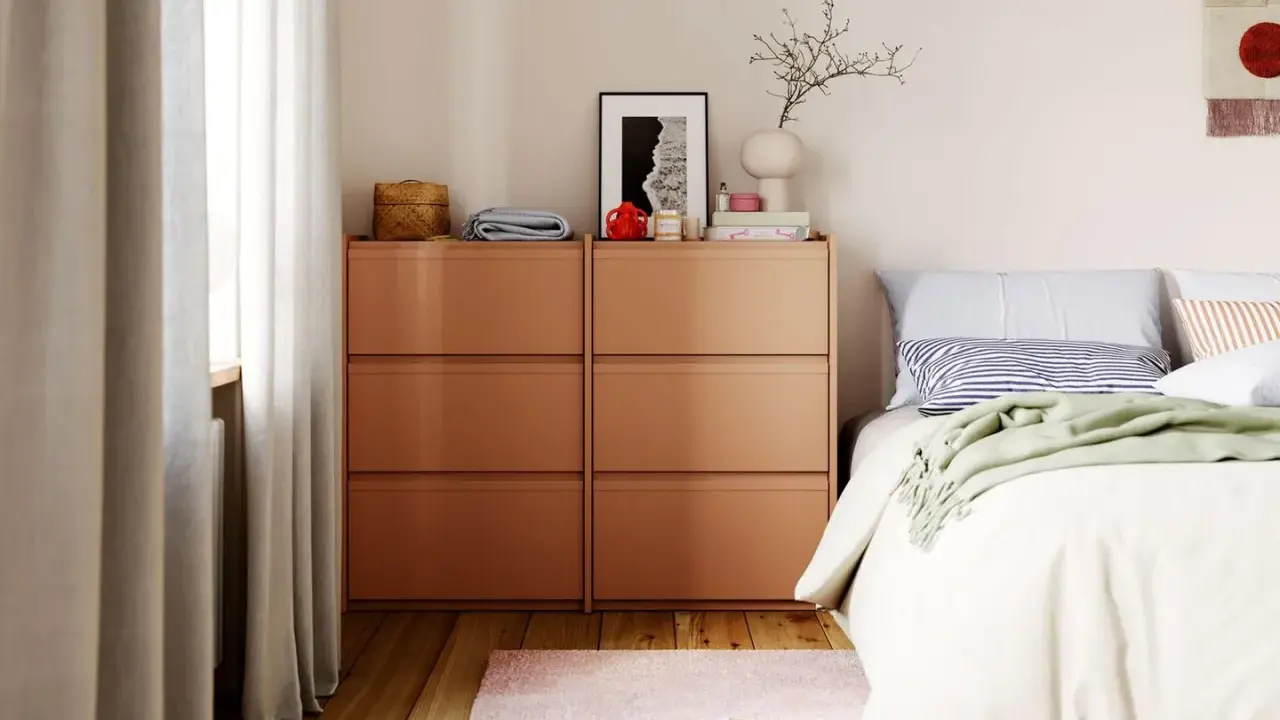 Ordnung im Schlafzimmer: Ein Nachttisch mit Schubladen, Bettwäsche und Dekoration.