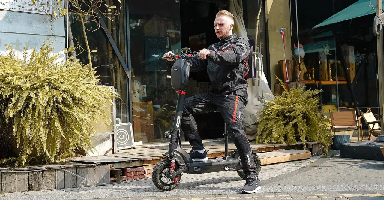 Un homme en tenue de moto est prêt pour un trajet de 10 km en trottinette électrique. Le temps est parfait pour explorer la ville.