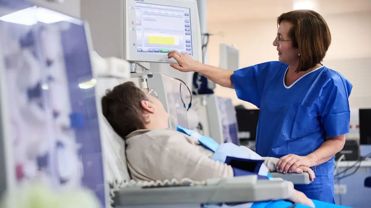 Pielęgniarka monitoruje parametry pacjenta po dializie. Pacjent leży, czując osłabienie po zabiegu.