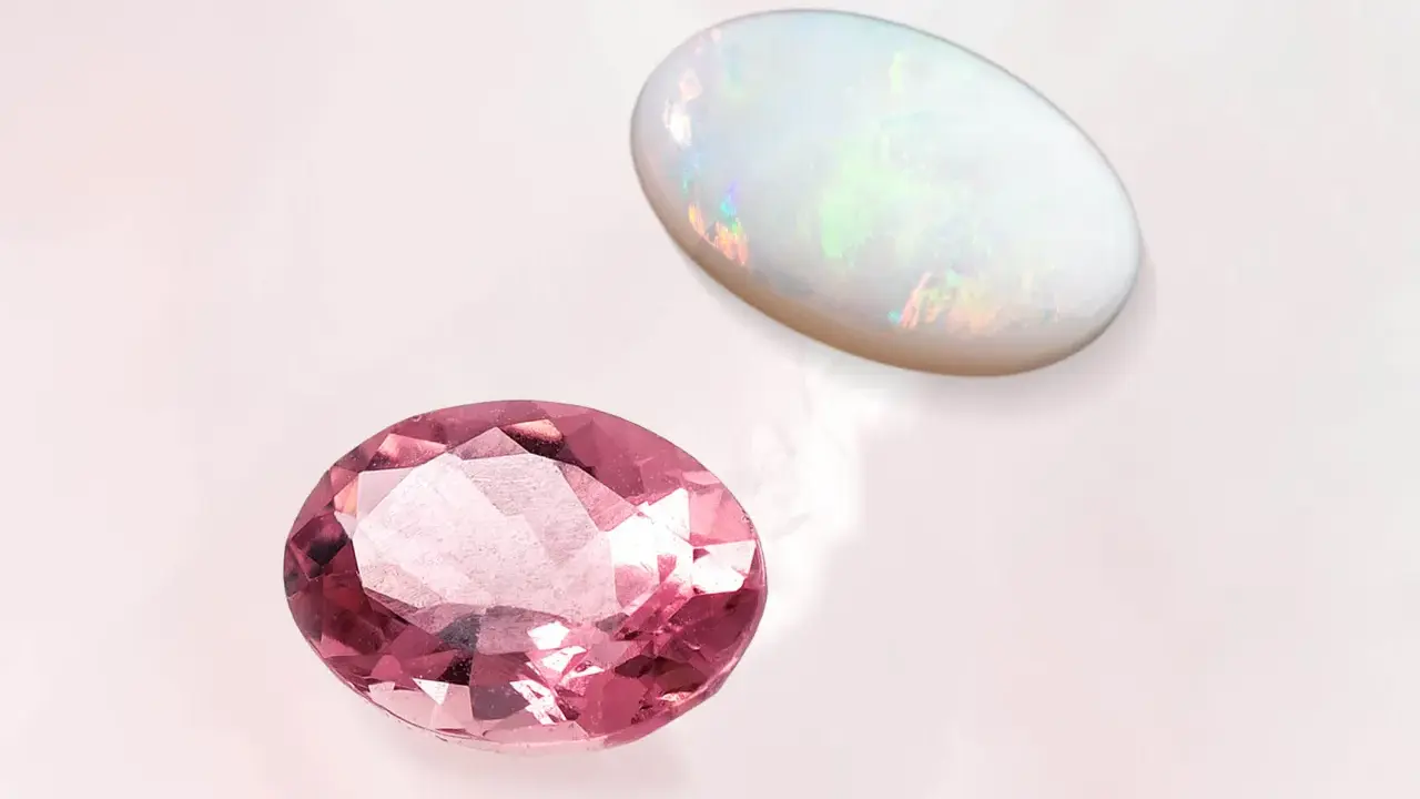 Due gemme ovali, una rosa e un opale, brillano su sfondo chiaro. La pietra rosa ricorda la pietra d'ottobre.