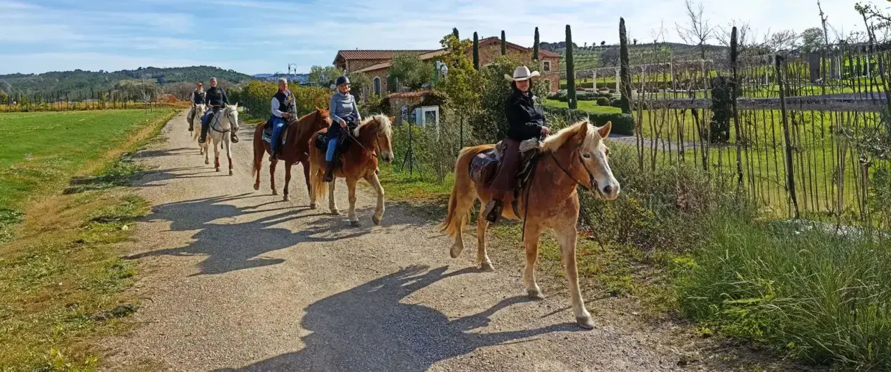 Cavalcata in un maneggio toscana, tra colline verdi e casali antichi.