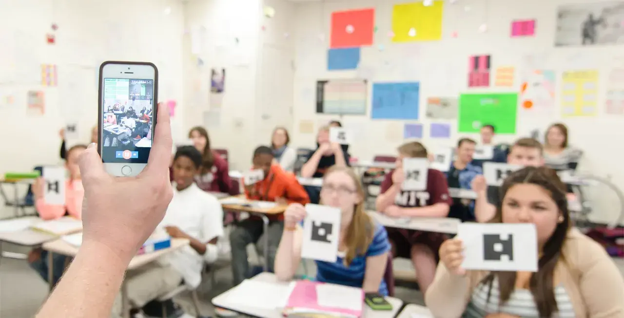 Classe che usa un'app per la scuola, con studenti che mostrano carte con simboli.