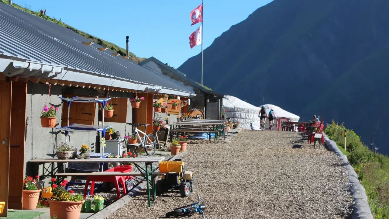 Górskie schronisko, idealne na przerwę podczas tour de Mont Blanc. Dwa rowery, szwajcarskie flagi i piękne widoki.