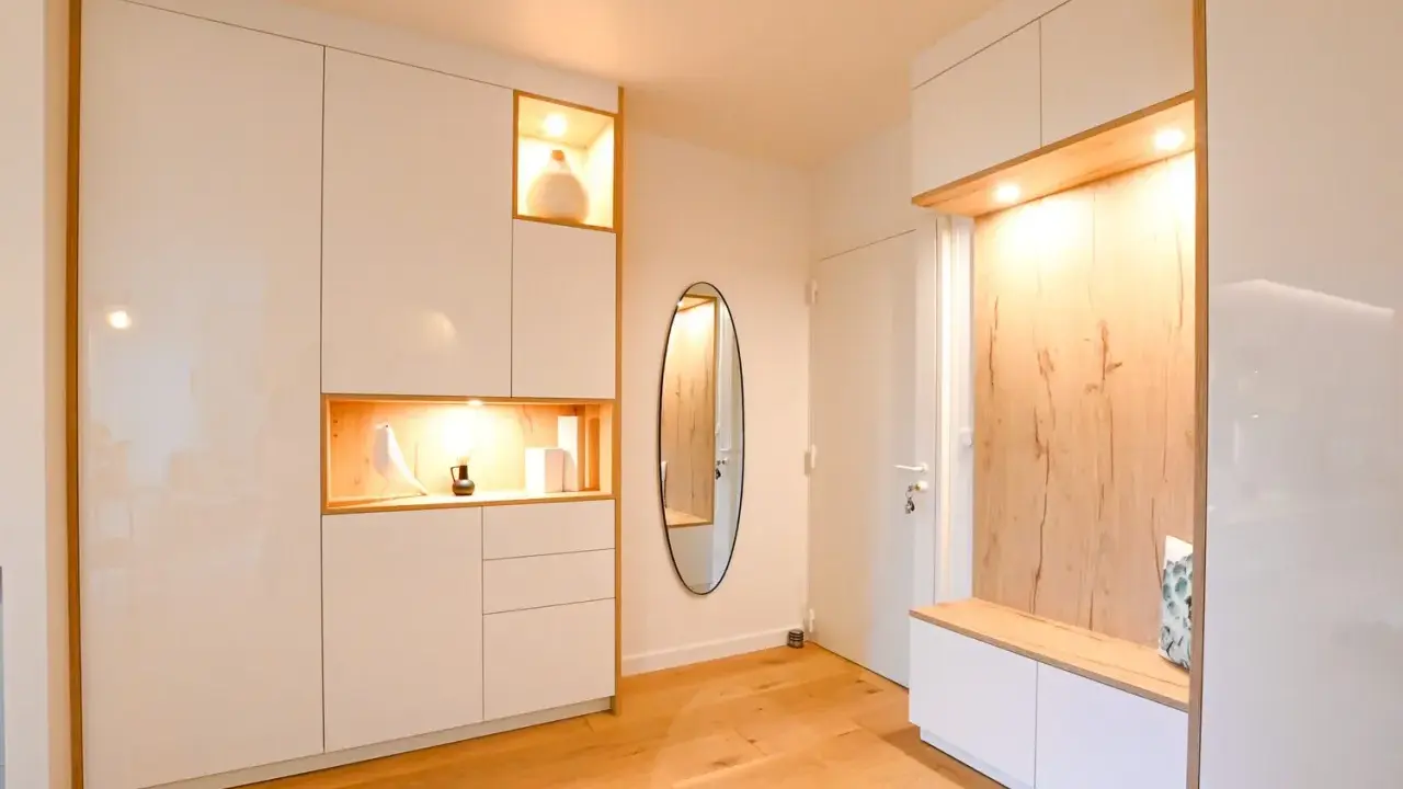 Ambiance chaleureuse dans cet intérieur de Kelt 550, avec des rangements blancs laqués et des niches en bois illuminées. Un miroir ovale ajoute une touche d'élégance.