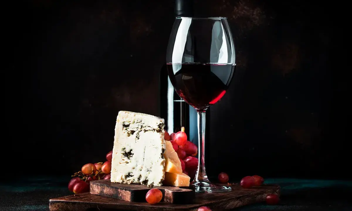 Ein Glas Rotwein, Käse und Trauben. Was ist Portwein? Ein süßer, aufgespriteter Wein, der oft zu Käse serviert wird.