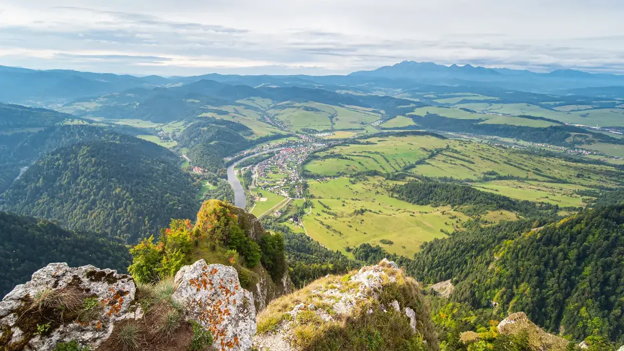 Widok z góry na dolinę z rzeką i miasteczkiem, w oddali majaczą Tatry. Trzy Korony w pełnej krasie.